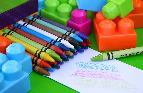 Many crayons and educational toys with some scribbles